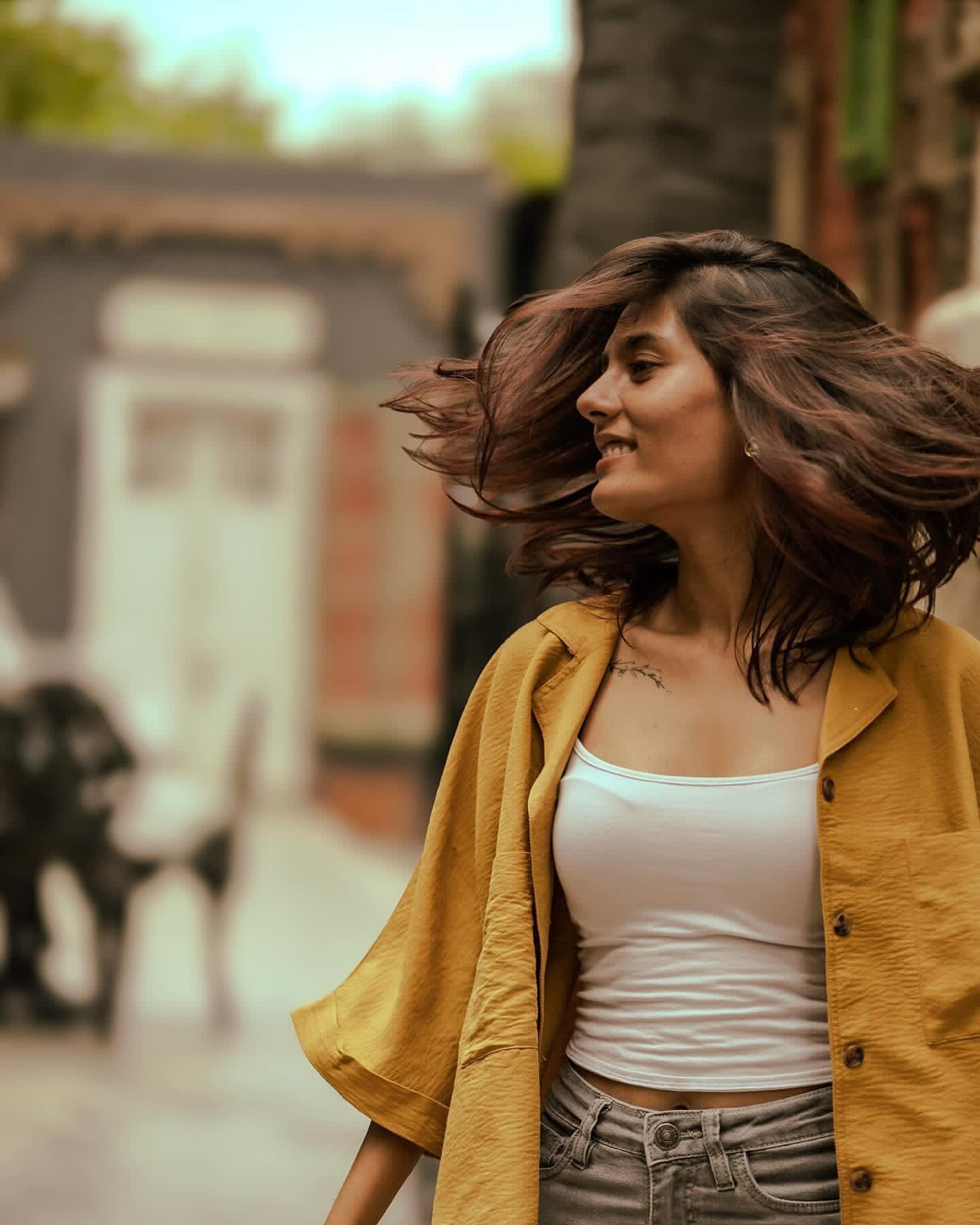 Woman in a mustard shirt turning, hair in motion — photograph by Nandika Shah